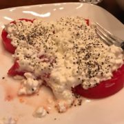la-food-bank_my-favorite-meal-MyFavoriteMeal-3-1-180x180 A plate with sliced tomatoes topped with creamy cottage cheese and sprinkled with black pepper, reminiscent of fresh produce often donated to the Los Angeles Regional Food Bank. A fork is placed on the side.
