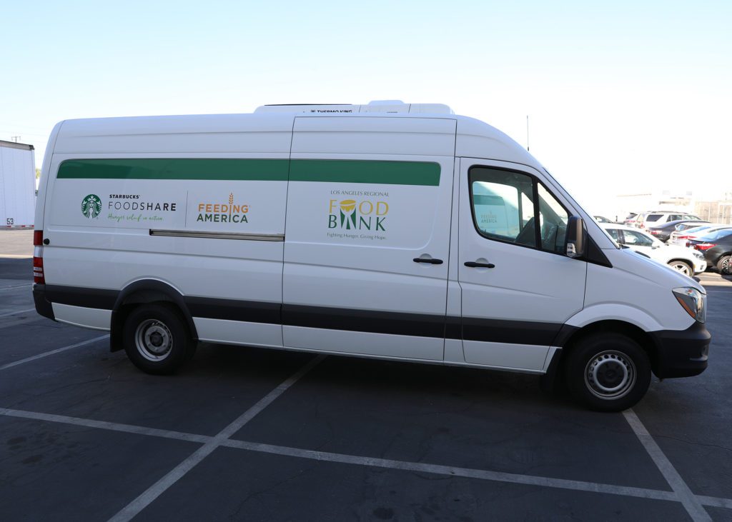 A white van is parked in a lot, boasting logos of 