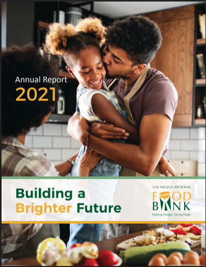 In a bustling kitchen, a person joyfully lifts a child as another looks on. The scene reflects the dedication of the Los Angeles Regional Food Bank, with text reading "Annual Report 2021" and "Building a Brighter Future.
