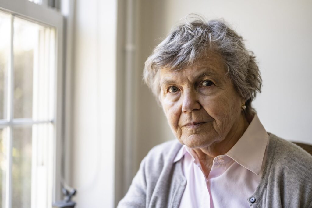 An older woman sits by a window