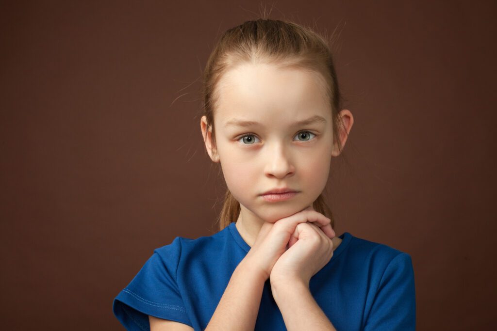 studio portrait of a 9 year old girl on a brown background