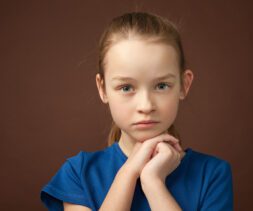 studio portrait of a 9 year old girl on a brown background