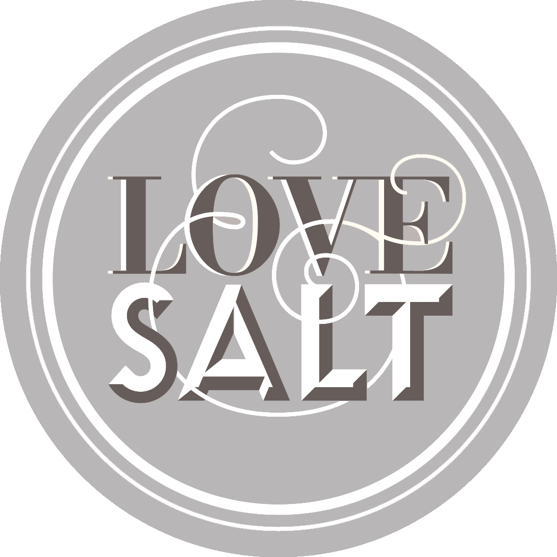 Gray circular logo with "LOVE & SALT" in bold, stylized letters at the center, reminiscent of partnership efforts like those with the Los Angeles Regional Food Bank. Curved and swirling lines add decorative elements around the text.