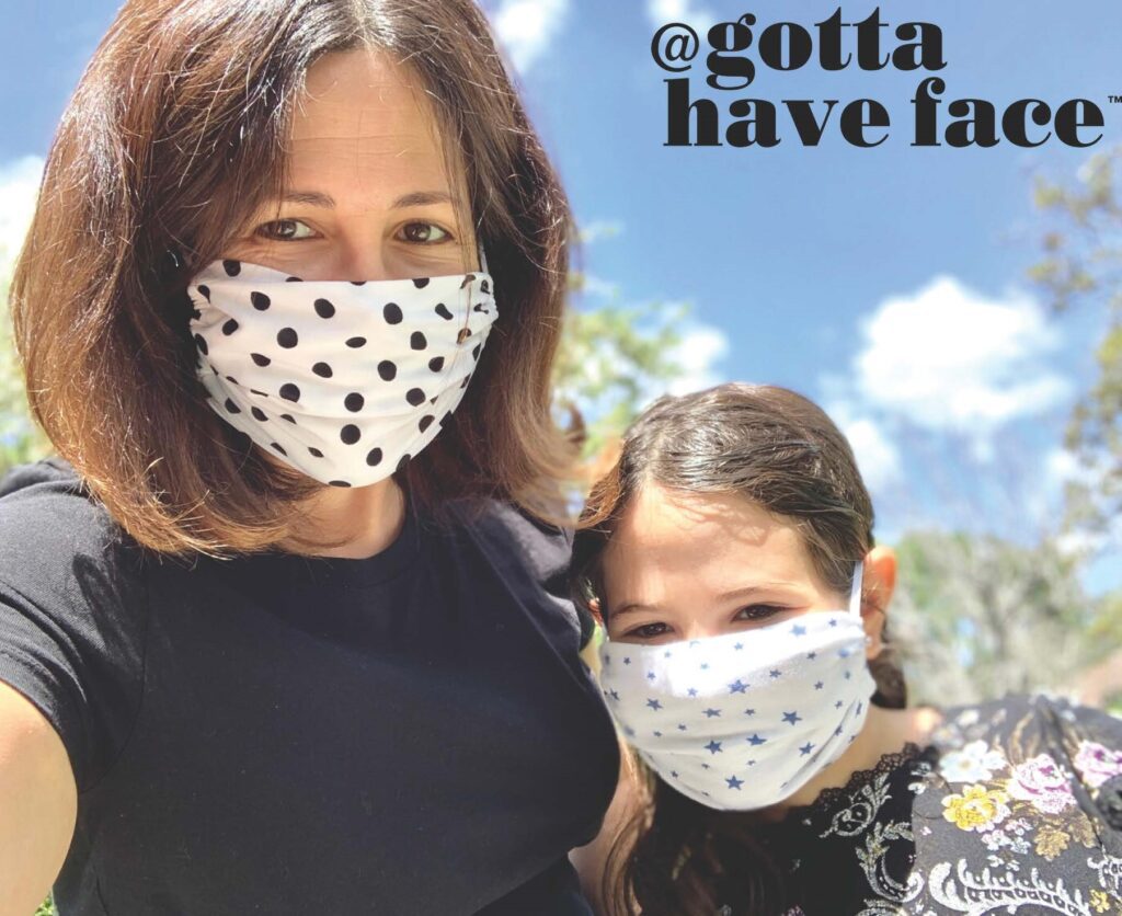 Two people wearing patterned face masks, one with polka dots and the other with stars, are standing outside on a sunny day in support of the Los Angeles Regional Food Bank. They're smiling brightly, and "@gottahaveface" is written in the top right corner.