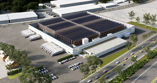 An aerial view captures a large logistics facility, reminiscent of the Los Angeles Regional Food Bank, with several warehouses surrounded by parked trucks and cars. The complex includes an open area with stacked containers, bordered by tree-lined streets and moving vehicles.