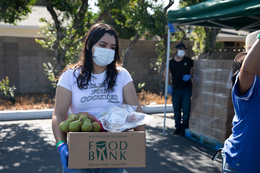 student volunteer loads food boxes onto car at Cerritos College