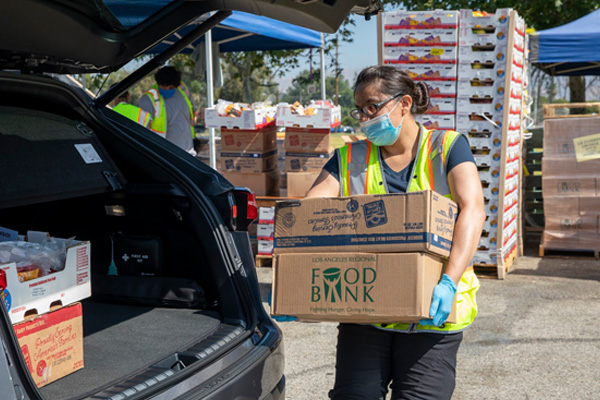 A volunteer loads food boxes onto a car