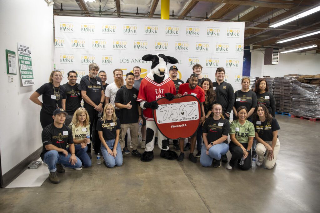 A group of people poses with a cow mascot holding a sign that reads 