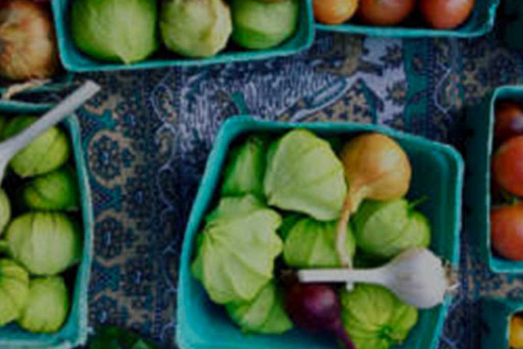 LAFB-Ways-to-give-Endowment Baskets brimming with fresh vegetables, such as tomatillos, onions, garlic, and tomatoes, are artfully arranged on a patterned tablecloth—thanks to the efforts of the Los Angeles Regional Food Bank.